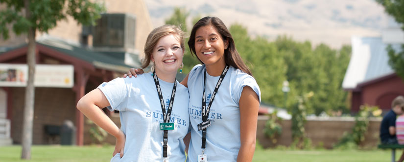 two teenager girls in blue shirts with lanyards stand with arms around each other