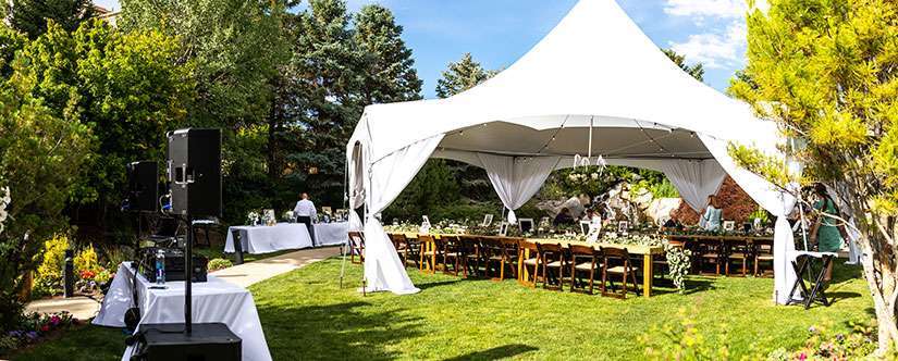 photo of large white tent with open sides, with decorated tables underneath