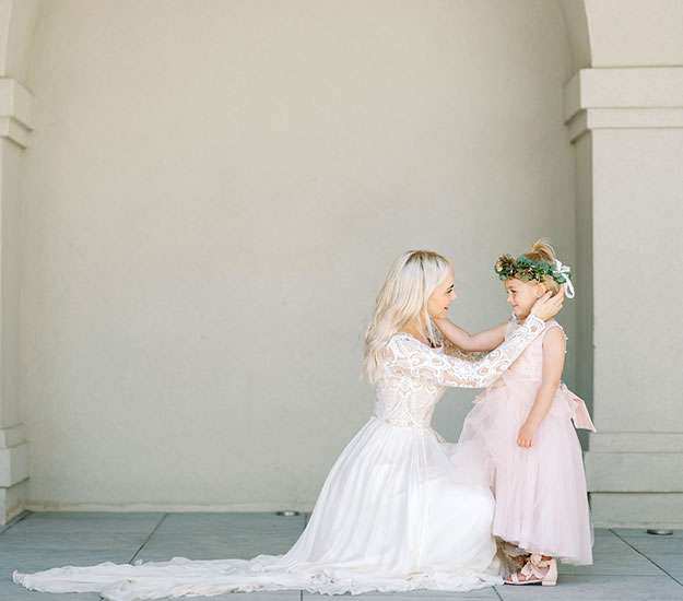 A bride helps a flower girl with her dress