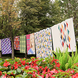 quilts hanging in front of flowers in garden