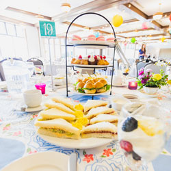 a plate of finger sandwiches in front of 3 tier tray with deserts