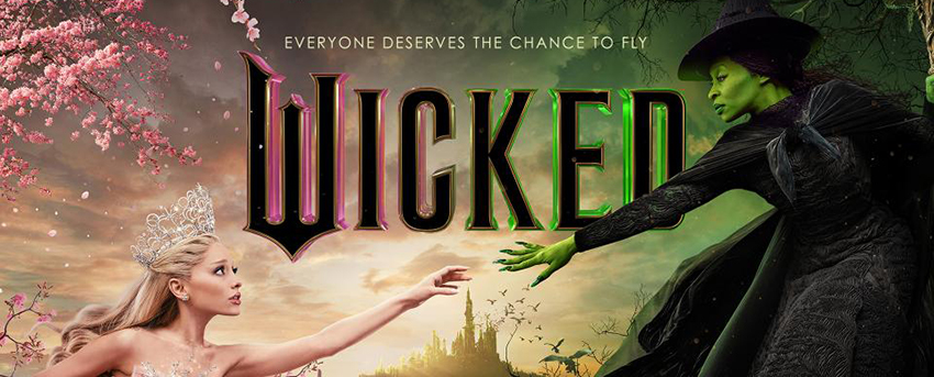 Wicked movie poster - Glinda is blond with crystal crown reachin to the right to Elphaba in black dress and pointy witch hat with green skin