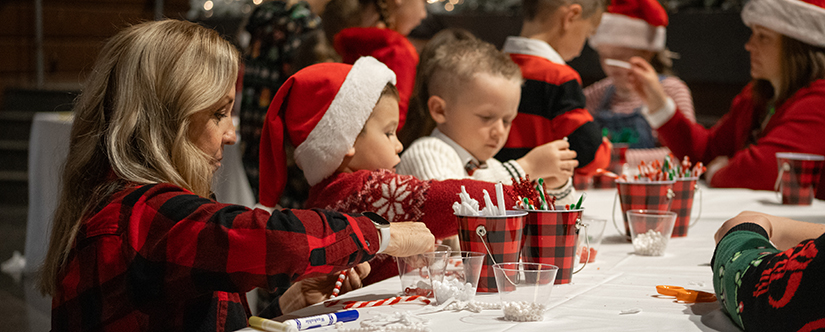 kinds working on craft at table while wearing santa hats