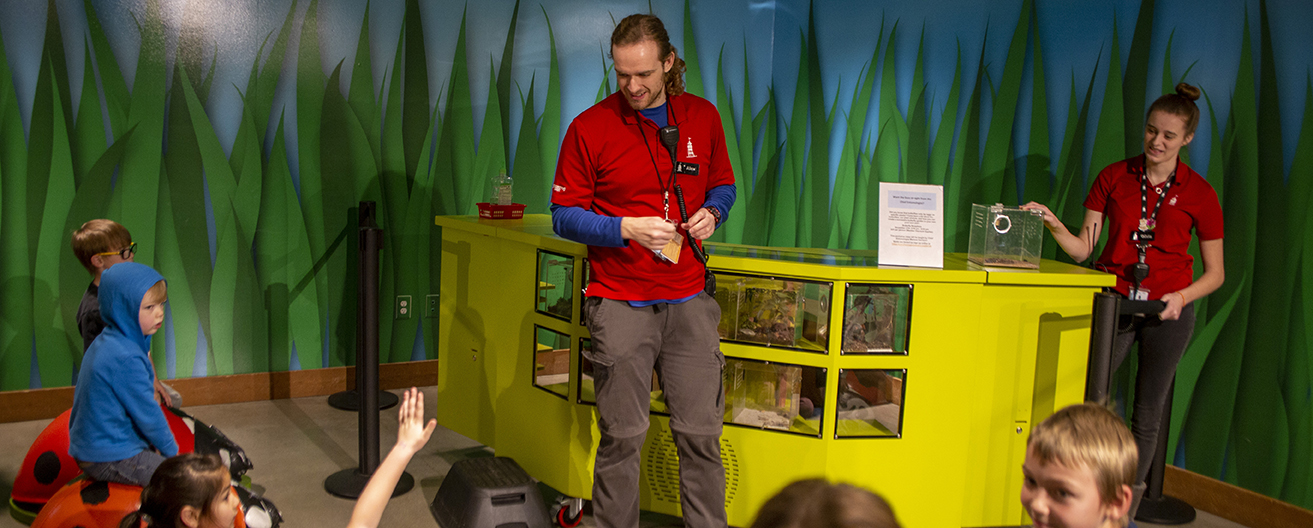 two employees in front of seated children for small presentation