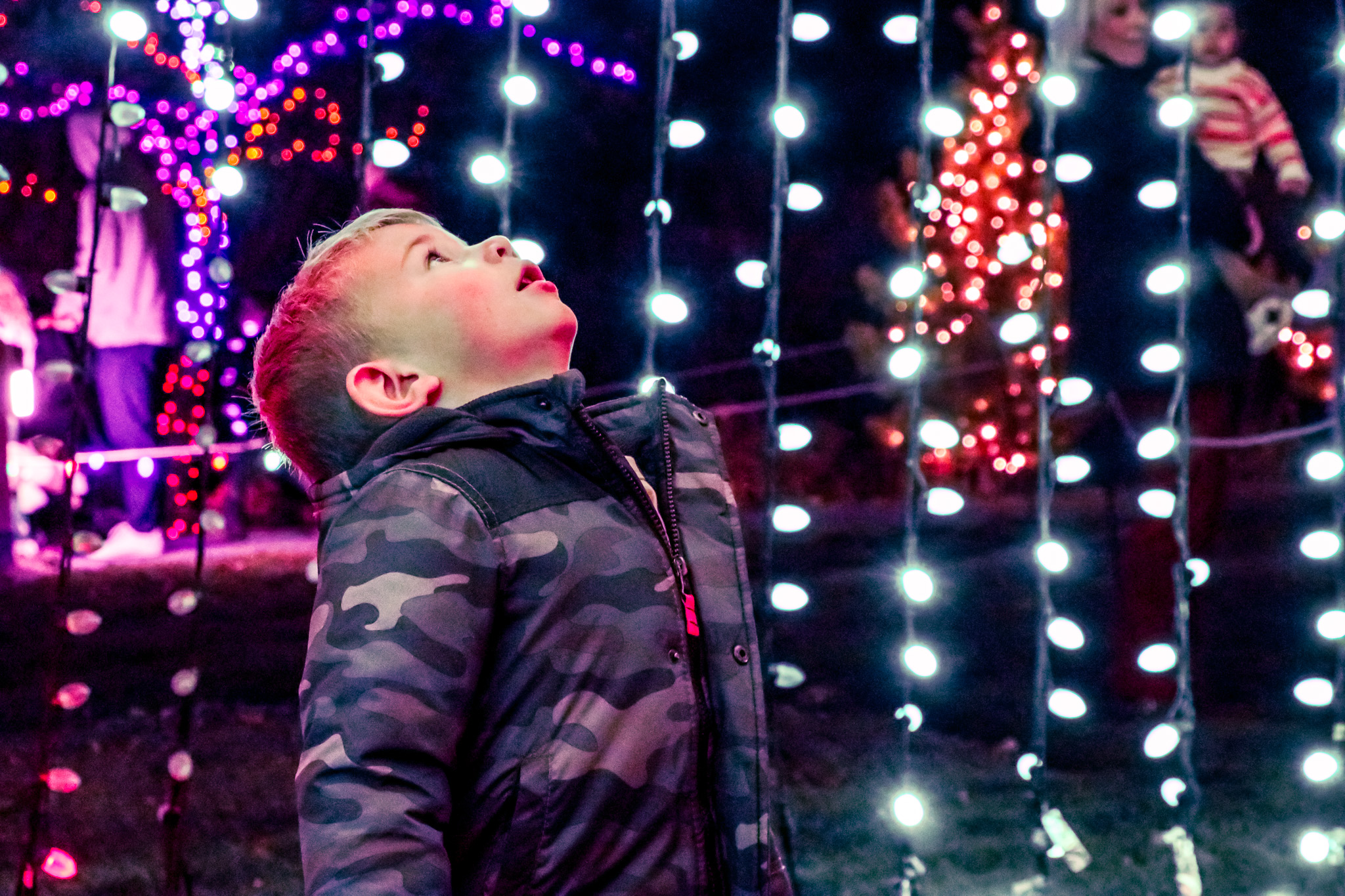 Child surrounded by illuminated strands at Luminaria