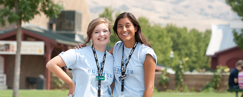 two teenage girls smiling outdoors with thanksgiving point lanyards