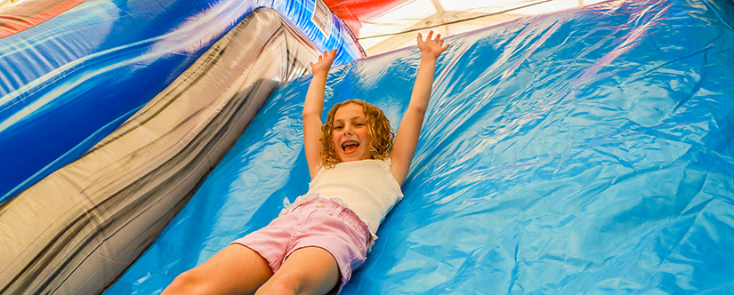girl in obstacle course sliding down slide
