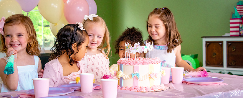 young girls laughing in front of cake decorated with carousel horses